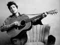 Bob Dylan playing guitar on a chair